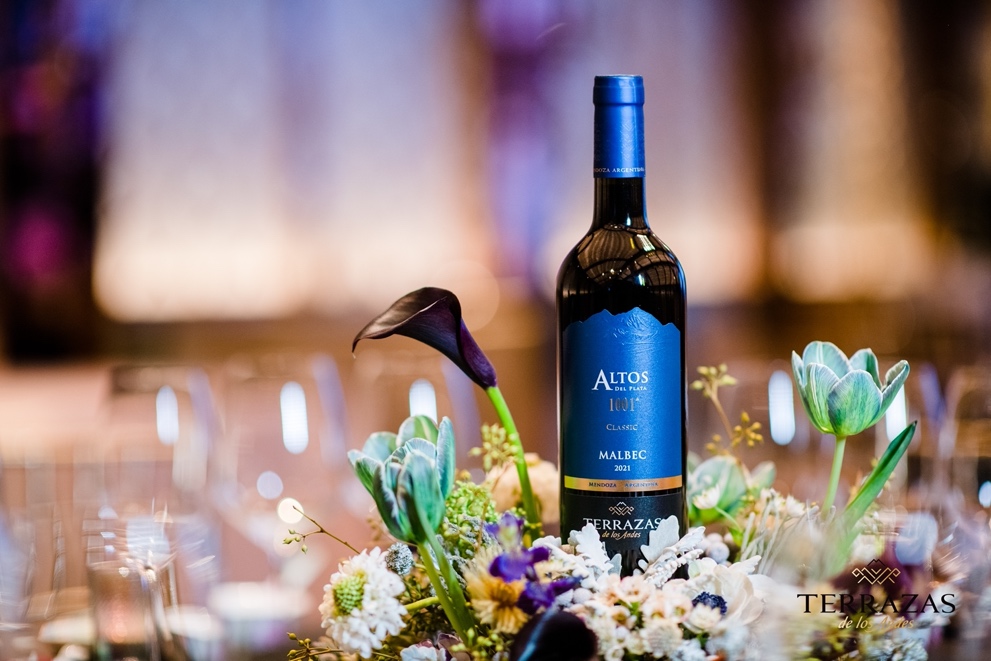 A bottle of wine next to a bouquet of flowers<em></em><em></em><em></em><em></em><em></em>
<em></em><em></em><em></em><em></em><em></em>
Des<em></em>cription automatically generated with medium confidence